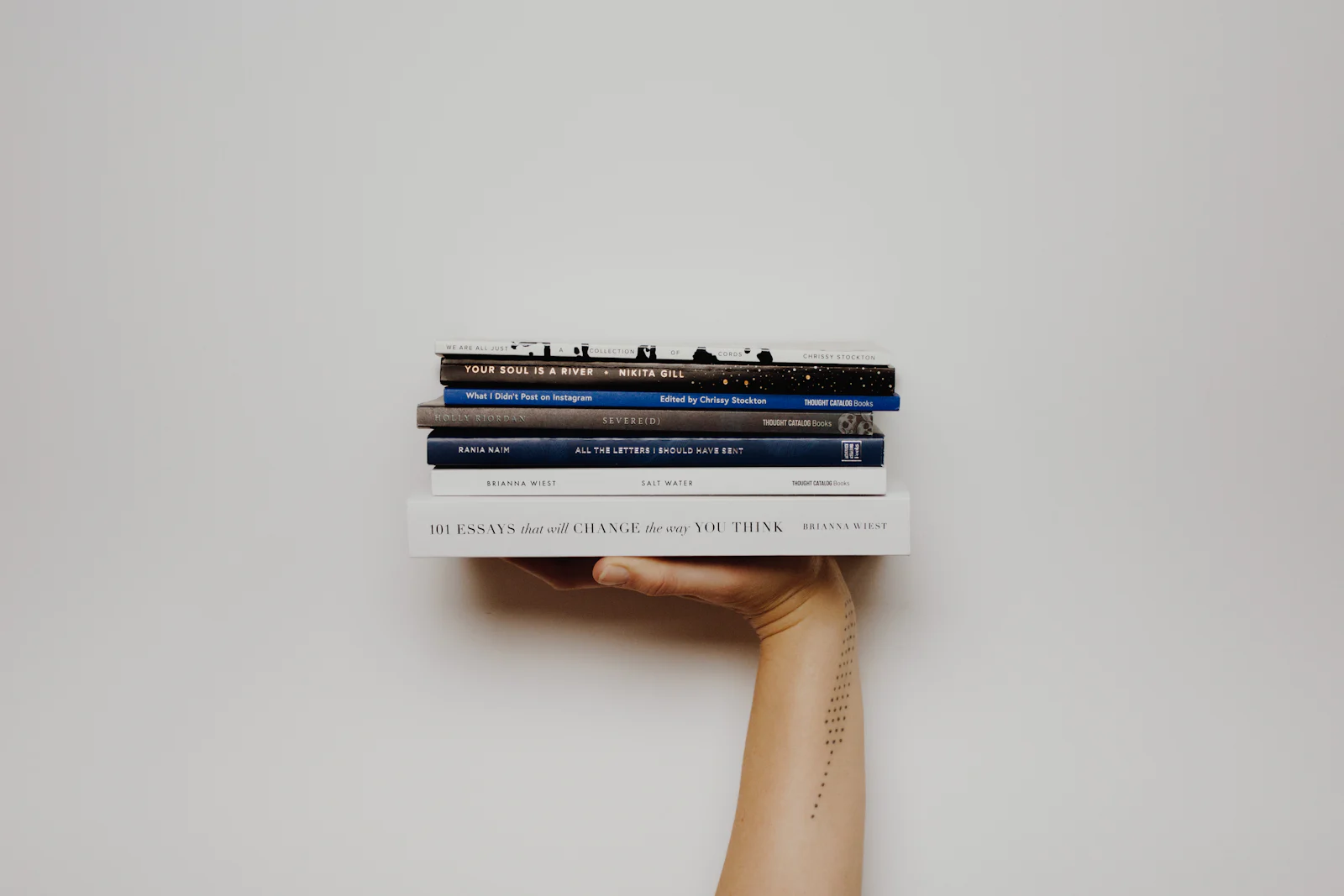 A hand holding a stack of bound books